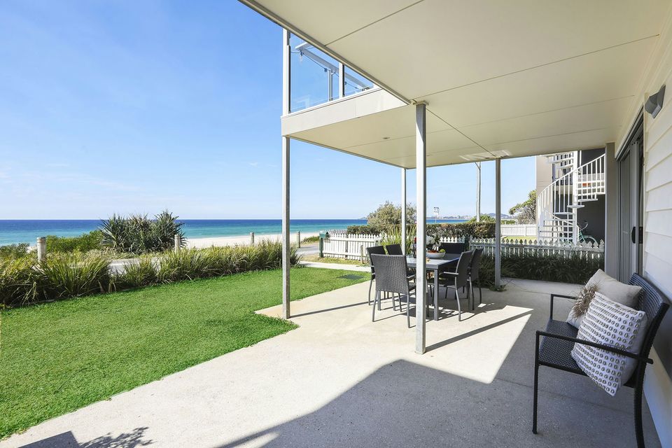 Shaded ground-floor terrace and lawn looking out to the ocean at Sandbox Apartments